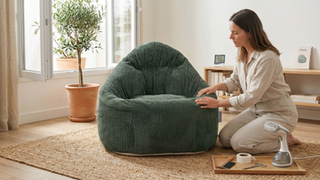 Femme qui prend soin du tissu de son pouf vert émeraude en velours côtelé dans son coin salon bohème
