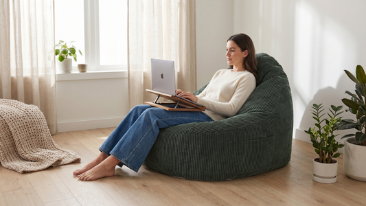 Femme qui travaille sur son ordinateur surélevé assise dans un grand pouf vert émeraude en velours côtelé avec un dossier.